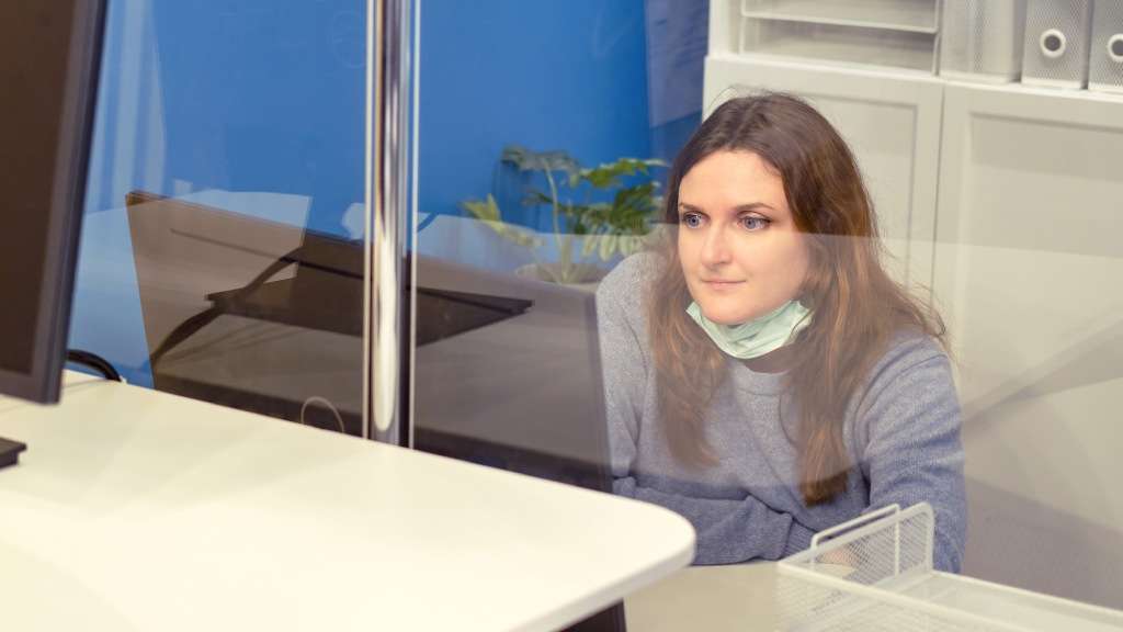 Woman working in an office behind a protective screen